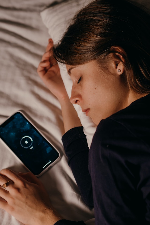 Image showing a lady taking sleep and away from mobile phone, shortening screen time.